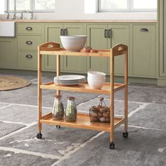 a kitchen cart with plates and bowls on it in the middle of a tile floor