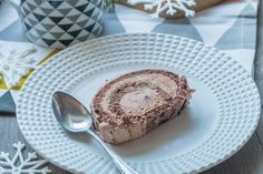 a piece of cake on a white plate with a spoon and snowflakes in the background