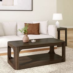 a living room with a white couch and wooden coffee table in front of a painting on the wall