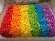 there is a rainbow cake with roses on the top and bottom layer in different colors