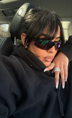 a woman wearing sunglasses sitting in the back seat of a car with her hand on her shoulder