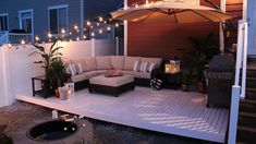 an outdoor living area with patio furniture and string lights on the side of the house