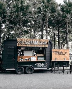 the coffee truck is parked in front of some tables with chairs and trees behind it