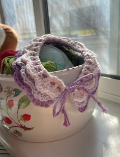 there is a crocheted pot holder on the window sill with yarn in it