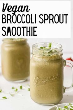 two mason jars filled with vegan broccoli sprout smoothie on a white surface