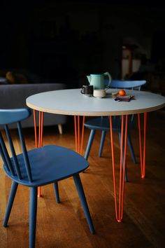 two chairs and a table in a room with wood flooring, one blue and the other orange