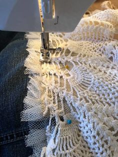 the sewing machine is working on the white lacy material that has been stitched together