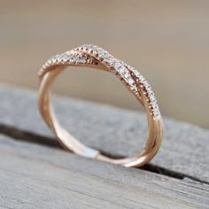 a gold ring with two rows of diamonds on it, sitting on top of a wooden surface