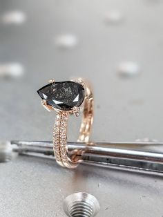 a black diamond ring sitting on top of a piece of metal next to a screw