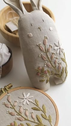 an embroidered bunny sitting next to two wooden hoop holders