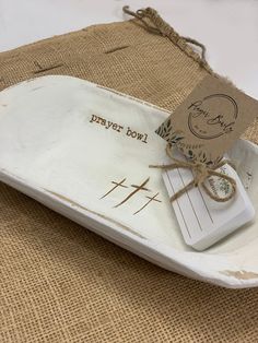 a small white tray with a tag on it that says prayer bowl and is tied in twine