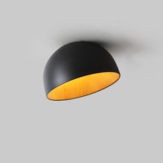 a black and yellow light hanging from a ceiling fixture on a gray wall in a room