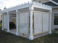 a white pergolated covered patio in front of a house with a bbq