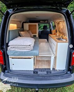 the back end of a van with an open trunk and bed in it's cargo area