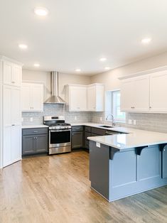 an empty kitchen with stainless steel appliances and white cabinets