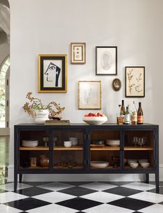 a black and white checkered floor with various framed pictures on the wall above it