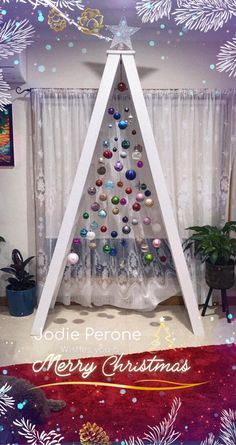 a christmas tree made out of ornaments in front of a window with the words jodie perone merry christmas