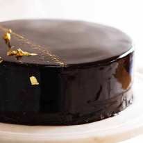 a chocolate cake with gold leaf decorations on it's top and bottom layer, sitting on a white plate