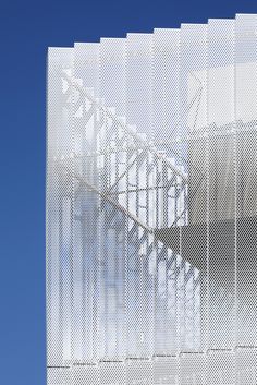 an abstract photo of a spiral staircase in front of a building with blue sky behind it