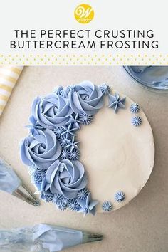 there is a blue frosted cake with icing flowers on it and the words, the perfect crusting buttercream frosting