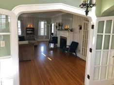 an open living room with hard wood flooring and white trim on the doors leading to another room