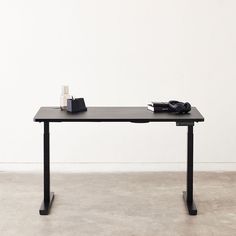 a black table with a phone and some books on it in front of a white wall