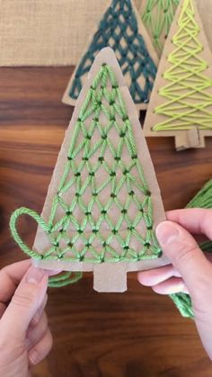 someone is making a small christmas tree out of string and yarns on a wooden table