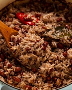 rice and beans are mixed together in a pot with a wooden spoon on the side