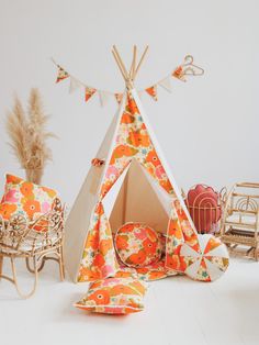 a teepee tent sitting on top of a white floor next to chairs and pillows