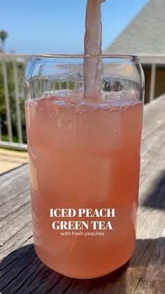 an iced peach green tea is being poured into a glass on a wooden table with the words iced peach green tea