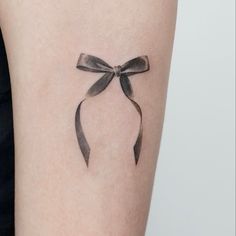 a woman's arm with a black bow tattoo on the left side of her body