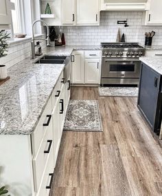 a kitchen with white cabinets and marble counter tops