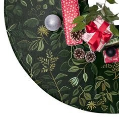 christmas presents are wrapped in red and green wrapping on a floral tablecloth with pine cones