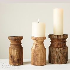 three wooden candlesticks sitting on top of a white table next to each other