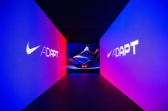 the nike logo is lit up in purple and blue light at the end of a tunnel