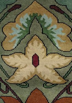 a close up view of a rug with flowers and leaves in the center, on green ground