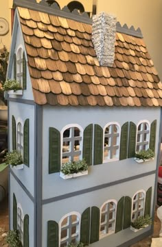 a doll house with green shutters and windows on the roof is shown in this image