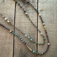 three beaded necklaces sitting on top of a wooden table