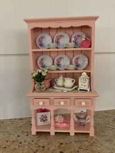 a pink china cabinet with plates and cups on it