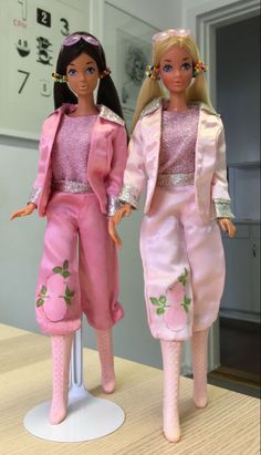 two barbie dolls standing next to each other