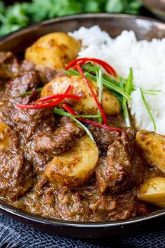 a close up of a plate of food with meat and potatoes on rice in it