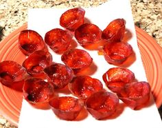 peeled plums on an orange plate sitting on a marble counter top next to a white paper towel