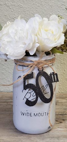 white flowers in a mason jar with the number 50 on it