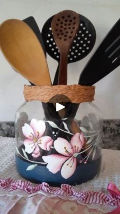 a glass jar filled with wooden spoons and spatulas on top of a table