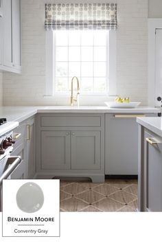 a kitchen with white cabinets and gray counter tops, along with a window above the sink