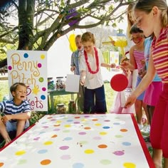 a group of children standing around a table with balloons and confetti on it