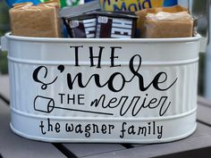 a white bucket filled with chocolates and candy bar wrapped in brown paper on top of a wooden table