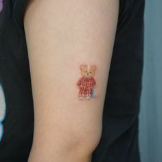 a small teddy bear tattoo on the arm