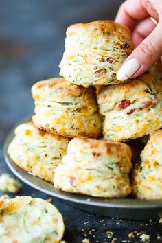 a hand picking up some biscuits from a plate on a table with other cookies in the background