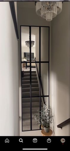 a hallway with a chandelier and mirror on the wall, next to stairs